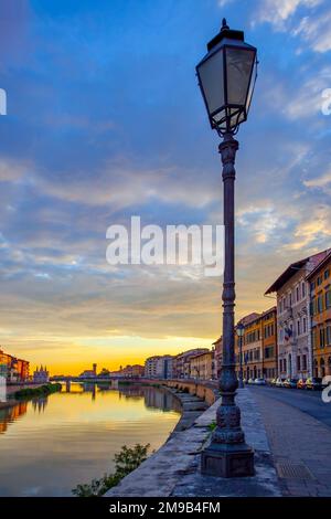 Blick auf Pisa mit dem Fluss Arno, wunderschöner Himmel bei Sonnenuntergang und alte Straßenbeleuchtung, Italien Stockfoto