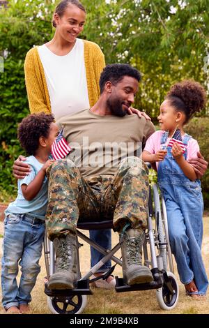 American Army Family Outdoors In Garden Mit Verletztem Vater Im Rollstuhl Stockfoto