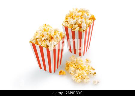 Zwei rot-weiß gestreifte Eimer mit leckerem Käsepopcorn, isoliert auf weißem Hintergrund. Film-, Kino- und Unterhaltungskonzept. Stockfoto