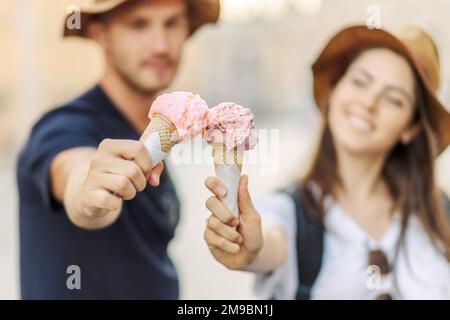 Glückliches Paar, das in Rom, Italien, Eis isst. Wunderschönes, helles Eis mit verschiedenen Geschmacksrichtungen in den Händen eines Paares Stockfoto