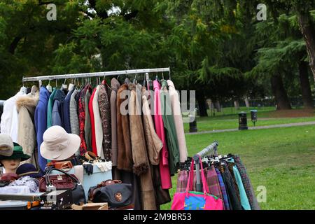 Alte gebrauchte Kleidung und neue Kleider im Stand auf dem Flohmarkt Stockfoto