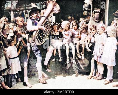 Das Foto zeigt eine Gruppe von Kindern, die einem Mann beim Tuba-Spielen in Berlin zuhören, kurz nach dem Ende des Zweiten Weltkriegs in Europa, August 1945. Stockfoto