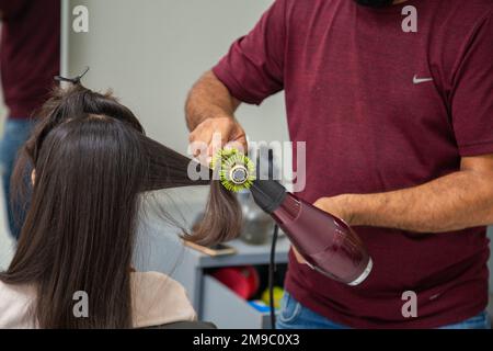 Goiania, Goiás, Brasilien – 10. Januar 2023: Detail eines Friseursalons mit Bürste und Trockner, Bürsten und Trocknen der Haare eines Kunden. Stockfoto