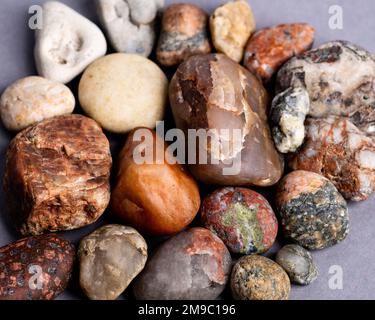 Eine Nahaufnahme der Natursteine, die sich gegenseitig auf einem lilafarbenen Hintergrund platzieren Stockfoto
