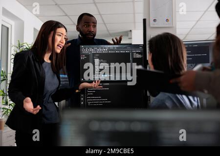 Verschiedene Webentwickler arbeiten gemeinsam an einem Programmierprojekt und sprechen über den Codierungsalgorithmus für die neue Cloud-Computing-Benutzeroberfläche. Team von Software-Ingenieuren, die Systemcode der Datenbank ausführen. Stockfoto