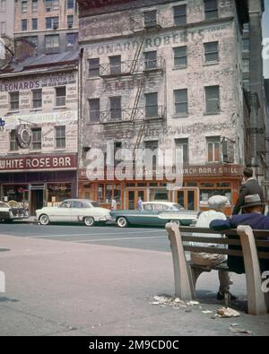 1950S 1960S GEBÄUDE MIT WERBUNG IN WHITEHALL UND SOUTH STREETS DOWNTOWN MANHATTAN NEW YORK CITY USA - KR132337 CPC001 HARS ARCHITEKTURÄLTESTER UNITED STATES COPY SPACE PEOPLE UNITED STATES OF AMERICA AUTOMOBIL MÄNNCHEN GEBÄUDE SENIOREN TRANSPORT SENIOREN IN DER INNENSTADT BAUWERK ALTE ALTE ALTE NACHBARSCHAFT ALTE GRUNDSTÜCKE STRASSEN UND AUTOS ÄUSSERE LOW ANGLE NYC BEMALTE ALTEN IMMOBILIEN NEW YORK STRUKTUREN AUTOS STÄDTE STOREFRONT FAHRZEUGE BAUWERK NEW YORK CITY MITTELERWACHSENER MANN, ALTMODISCHE SCHAUFENSTERFRONTEN WHITEHALL Stockfoto