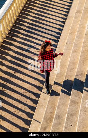 Ein junges Mädchen, das fröhlich auf einem sonnigen Steinweg spaziert; Fairmount Water Works; Philadelphia; Pennsylvania; USA Stockfoto