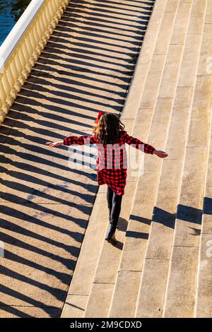 Ein junges Mädchen, das fröhlich auf einem sonnigen Steinweg spaziert; Fairmount Water Works; Philadelphia; Pennsylvania; USA Stockfoto