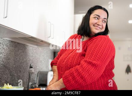 Eine körperbehinderte Frau bereitet das Mittagessen in der Küche zu. Stockfoto