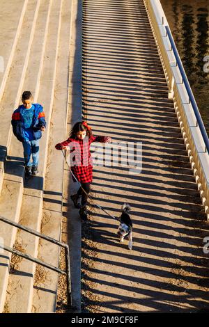 Junge und Mädchen mit Hund springen fröhlich über den sonnigen Steinweg; Fairmount Water Works; Philadelphia; Pennsylvania; USA Stockfoto