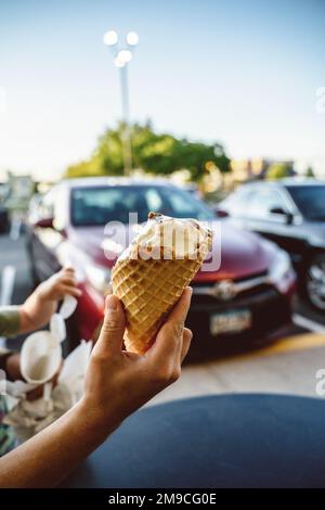 Hand hält im Sommer halb gefressenes Eis in Waffle Cone Stockfoto