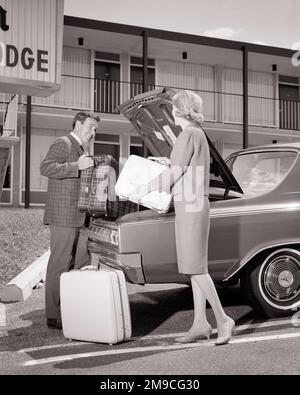 1960S LÄCHELNDER MANN UND LÄCHELNDE FRAU, DIE IHR GEPÄCK IN DEN KOFFERRAUM IHRES AUTOS VOR EINER MOTOR LODGE PARKEN MOTEL - M7260 HAR001 HARS FEMALES LODGE VERHEIRATETE EHEPARTNER EHEMÄNNER KOPIEREN WELTRAUMFREUNDSCHAFT VOLLE DAMEN PERSONEN MÄNNER KOFFERRAUM-MOTELTRANSPORT B&W PARTNER PARKT URLAUB ABENTEUER REISE UND KURZURLAUB EXTERIEUR FÜHRUNG NIEDERWINKELURLAUB ROAD TRIP CONNECTION STYLING SUPPORT IN KOOPERATIONSFRONT MITTELERWACHSENER MITTELERWACHSENER MANN MITTELERWACHSENER FRAUEN ZUSAMMENSEIN URLAUB EHEFRAUEN UNTERKUNFT SCHWARZ-WEISS WEISSE ETHNISCHE HERKUNFT HAR001 ALTMODISCH Stockfoto