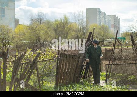 Alter Mann im Garten vor dem Hintergrund der Stadt. Stockfoto