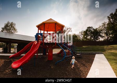 Das Kind rennt auf den Spielplatz im Park zu Stockfoto