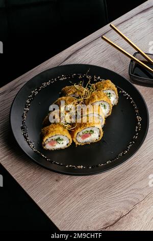 Tempura Sushi rollt auf einem schwarzen Teller Stockfoto