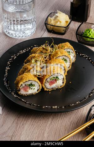 Tempura Sushi rollt auf einem schwarzen Teller Stockfoto