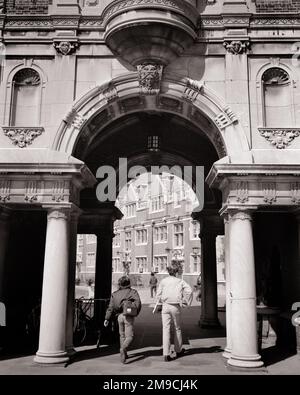 1970S ANONYME MÄNNLICHE STUDENTEN, DIE UNTER EINEM KUNSTVOLL VERZIERTEN ARCHITEKTURBOGEN AUF DEM COLLEGE CAMPUS LAUFEN - S19873 HAR001 HARS MÄNNLICHE TEENAGER GEBÄUDE B&W ZIELE STRUKTUR ARCHITEKTUR HOCHWINKELBOGEN ENTDECKUNGSANLAGE UNIVERSITÄTEN NETZWERKWISSEN KUNSTVOLL STOLZ AUSSICHT AUSSICHT AUSSICHT HOCHSCHULBILDUNG IMMOBILIENVERBUND KONZEPT VON STRUKTUREN TEENAGER COLLEGES GEBÄUDE ANONYM RÜCKBLICK ZUSAMMENARBEIT WACHSTUM ZUSAMMENGEHÖRIGKEIT JUNGER ERWACHSENER MANN SCHWARZ UND WEISSE, KAUKASISCHE ETHNISCHE ZUGEHÖRIGKEIT HAR001 ALTMODISCH Stockfoto