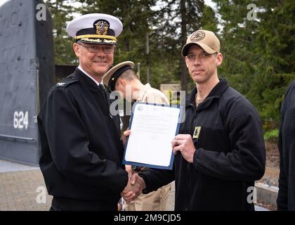 SILVERDALE, Washington (16. Mai 2022) – Kapitän Robert Figgs, Left, kommandierender Offizier der Trident Refit Facility, Bangor (TRFB), überreicht während einer Festpinnungszeremonie auf der Marinebasis Kitsap-Bangor einen überwältigenden Brief an Jeremy J. Dunn, das Mate-U-Boot des Chefmachinisten (Auxiliary). Das TRFB unterstützt die strategische Abschreckungsmission des Landes durch die Reparatur, schrittweise Überholung und Modernisierung strategischer U-Boote für ballistische Raketen der Pazifikflotte während der Umrüstung. Stockfoto