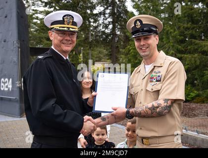 SILVERDALE, Washington (16. Mai 2022) – Kapitän Robert Figgs, Left, befehlshabender Offizier der Trident Refit Facility, Bangor (TRFB), überreicht während einer Festpinnungszeremonie auf der Marinebasis Kitsap-Bangor einen überwältigenden Brief an den leitenden Chief Hull Maintenance Technician Jonathan Espersen. Das TRFB unterstützt die strategische Abschreckungsmission des Landes durch die Reparatur, schrittweise Überholung und Modernisierung strategischer U-Boote für ballistische Raketen der Pazifikflotte während der Umrüstung. Stockfoto