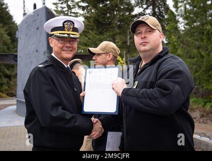 SILVERDALE, Washington (16. Mai 2022) – Kapitän Robert Figgs, Left, befehlshabender Offizier der Trident Refit Facility, Bangor (TRFB), überreicht während einer Festpinnungszeremonie auf der Marinebasis Kitsap-Bangor einen frostigen Brief an den leitenden Häuptling Hull Maintenance Technician Joseph Kemnitz. Das TRFB unterstützt die strategische Abschreckungsmission des Landes durch die Reparatur, schrittweise Überholung und Modernisierung strategischer U-Boote für ballistische Raketen der Pazifikflotte während der Umrüstung. Stockfoto