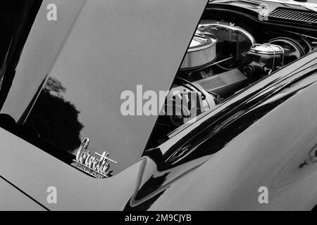 Die offene Motorhaube und der Motorraum eines alten Corvette Sting Ray Autos auf einer Automesse in Essex, Massachusetts. Das Bild wurde in Schwarz aufgenommen Stockfoto