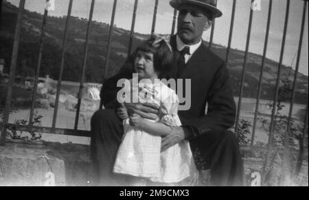 Ein kleines Mädchen steht mit ihrem Großvater vor ein paar Geländern Stockfoto