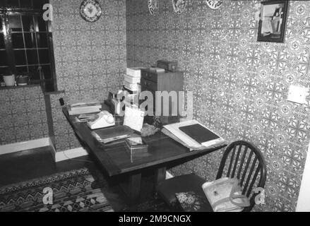 Studium eines Hauses im Stil der 1930er Jahre mit Tischkalender, montierten Tellern und Tapeten mit Blumendruck Stockfoto