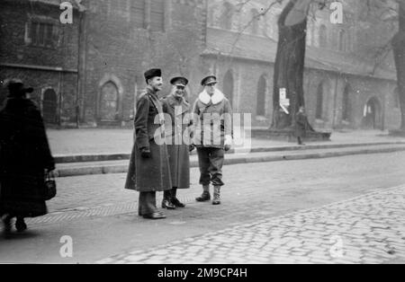 Drei britische Armeeoffiziere in einer nicht identifizierten Stadt in Deutschland gegen Ende des Zweiten Weltkriegs, fotografiert auf der Straße in der Nähe des Rathauses. Stockfoto