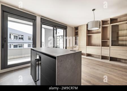 Apartment mit Küche zum Wohnzimmer mit maßgefertigten Eichenbüchern und Fenstern mit Schiebetüren, die zu einer großen Terrasse führen Stockfoto
