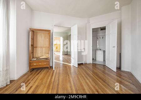 Leeres Haus mit einigen losen Holzmöbeln, wie einem Schrank ohne Tür, Zugang zum Badezimmer und Holzfußboden Stockfoto