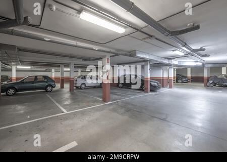 Erdgeschoss eines Gebäudes, das einer Garage gewidmet ist, mit einem Zementboden und weiß lackierten Räumen Stockfoto