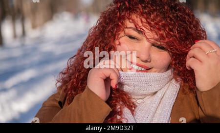 Porträt einer lächelnden, kubigen, rothaarigen Frau auf einem Winterspaziergang. Stockfoto