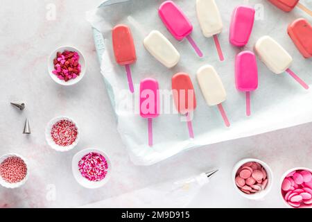 Undekorierte Kuchenpopps mit verschiedenen Streuseln und überall schmelzende Süßigkeiten. Stockfoto