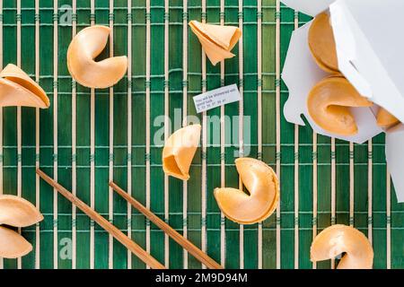 Glückskekse auf einer Bambusmatte mit Stäbchen und einem Vermögen. Stockfoto