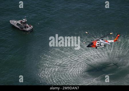 Die Besatzung an Bord eines MH-60 Jayhawk von der Luftwaffe der Küstenwache Elizabeth City bereitet sich darauf vor, zwei Navy-Piloten vom Navy Strike Fighter Atlantic aus dem 47-Fuß-Motorlebensboot der Küstenwache zu heben, besetzt von Mitgliedern der Station Indian River Inlet während der gemeinsamen Such- und Rettungsübung am 17. Mai, 2022, in der Nähe von Ocean City, Maryland. Die Such- und Rettungsübung ist eine jährliche Veranstaltung, die die Küstenwache, die Marine und die Luftwaffe auf Such- und Rettungssituationen vorbereitet, die eine Koordinierung zwischen den Diensten erfordern können. Stockfoto