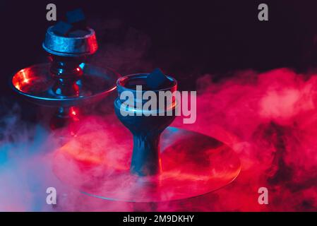 Hookah-Schüssel und Kohlen werden auf schwarzem Hintergrund mit Rauch geschlossen Stockfoto