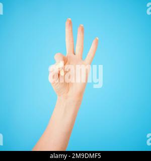 Nicht jede Kommunikation ist verbal. Studiofoto einer nicht erkennbaren Frau mit drei Fingern vor blauem Hintergrund. Stockfoto