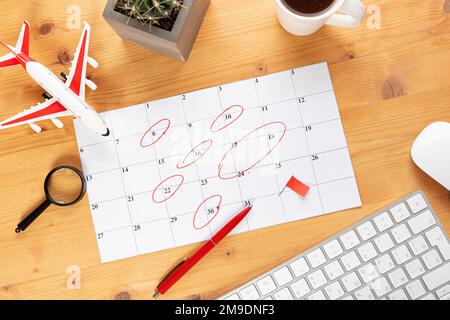 Kalender und Erinnerungen für Geschäftsreisen, Reisen und Urlaub. Gleiter auf dem Schreibtisch mit Flugzeug und Lupe, Stift und Tastatur. Markierung wichtig Stockfoto