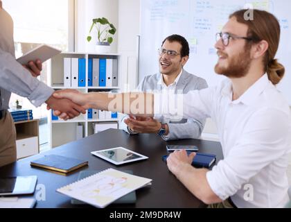 Schön, dass Sie bei uns sind. Eine vielfältige Gruppe von Geschäftsleuten, die während einer Besprechung im Büro die Hand schütteln. Stockfoto
