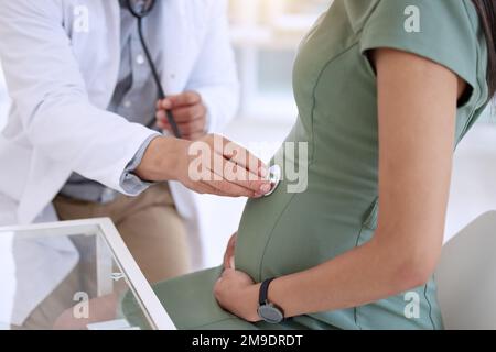 Ich kann hören, wie sich Ihr Kind bewegt. Ein unerkannter Arzt, der während einer Untersuchung mit seiner schwangeren Patientin ein Stethoskop benutzt. Stockfoto