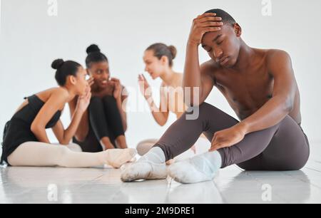 Unsere dramatische Leistung fühlt sich zu real an. Ein Teenager sieht traurig aus, während der Rest seiner Ballettklasse hinter seinem Rücken über ihn spricht. Stockfoto