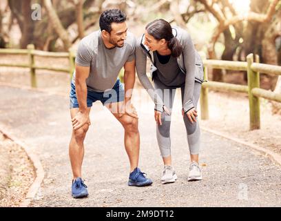 Paare, die zusammen trainieren, gewinnen zusammen. Ein junger Mann und eine junge Frau, die in der Natur joggen. Stockfoto