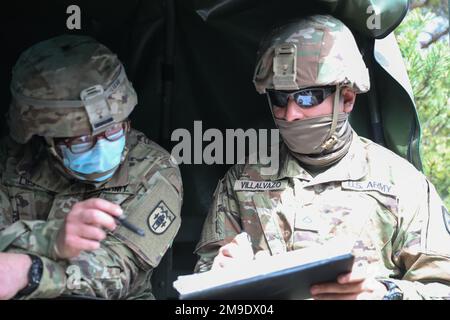 Von links Armee-Staff Sgt. Dennis Liehr und USA Pablo Villalvazo, zugeteilt in Charlie Battery 119. Field Artillery, Michigan Army National Guard, geht das Szenario durch und bewertet die Richtigkeit der Anrufe nach einem Aufruf zur Feuerschulung zur Vorbereitung auf ihre Feuerübungen während der Übung Summer Shield 22 an der Einsatzstelle Adazi, Lettland, 18. Mai 2022. Summer Shield ist einer von den USA Die multinationalen Ausbildungsübungen der Armee Europa und Afrikas in Osteuropa, die Defender Europe 22 bilden. Defender demonstriert U.S. Die Fähigkeit der Armee Europas und Afrikas, große... Stockfoto