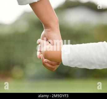 Die Welt, geheiratet entdeckt, liebt nicht wie die Familie. Ein kleines Mädchen, das die Hand seiner Mutter hält, während es einen Spaziergang im Park macht. Stockfoto