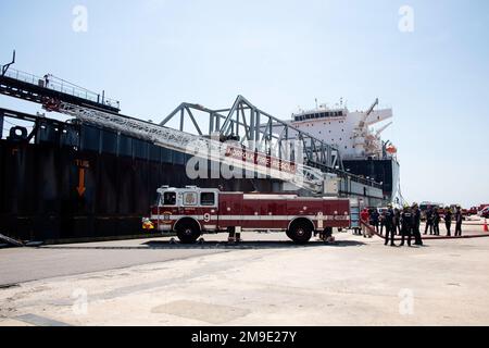 Studenten des Maritime Incident Response Team (MIRT) des Hafens von Virginia führen an Bord der USNS Montford Point (T-ESD 1) eine Schulung zur Brandbekämpfung durch. Die Schulung war Teil eines einwöchigen MIRT-Symposiums, bei dem mehr als 120 Feuerwehrleute aus verschiedenen Ländern in der Region zusammenkamen, um auf Seeunfälle zu reagieren. Stockfoto