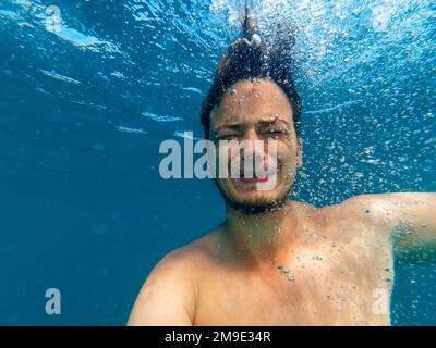 Ein Mann unter Wasser, ertrinkt mit einem Ausdruck von Angst und Horror auf ihrem Gesicht und wartet auf Hilfe Stockfoto