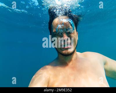Ein Mann unter Wasser, ertrinkt mit einem Ausdruck der Angst und ruft um Hilfe Stockfoto