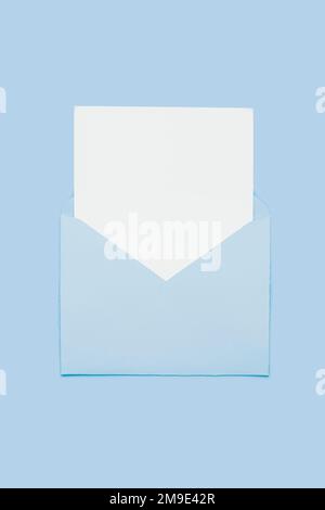Nahaufnahme auf leerer weißer Papierkarte in blauem, geöffnetem Umschlag isoliert auf blauem pastellfarbenem Hintergrund. Liebesbrief-Minimalkonzept. Konzeptionelle Layoutvorlage mit Textposition auf Postkarte. Modell Stockfoto