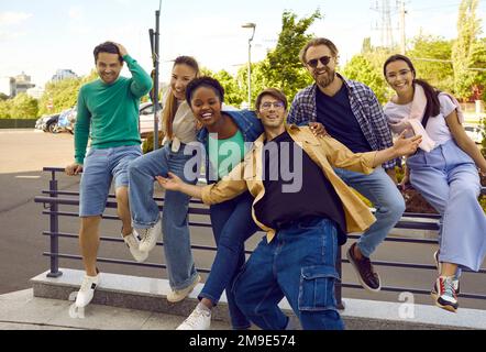 Fröhliche männliche und weibliche Freunde haben Spaß und lachen zusammen auf den Straßen der Stadt im Sommer. Stockfoto