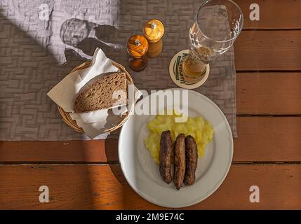 Bratwurst serviert mit Kartoffelsalat und Brot in einem Gasthaus in Bayern Stockfoto